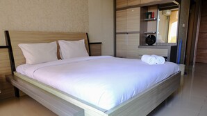 Ein modernes Hotelzimmer mit einem großen Bett, einem Holzkopfteil und einem eingebauten Wandschrank mit Spiegel.