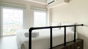 A hotel room with a bed, a window with a view, and an air conditioning unit. - Luxury And Minimalist Studio At Patraland Urbano Apartment (Bekasi)