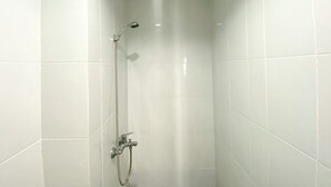 A small, white-tiled shower stall with a handheld showerhead and a handheld faucet. - Luxury And Minimalist Studio At Patraland Urbano Apartment (Bekasi)