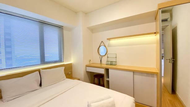 Ett hotellrum med en säng, ett skrivbord, en spegel och en garderob.