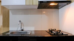 A kitchen with a black countertop, stainless steel sink, and a gas stove. - Best Location 2Br At Gateway Pasteur Apartment (Cimahi)