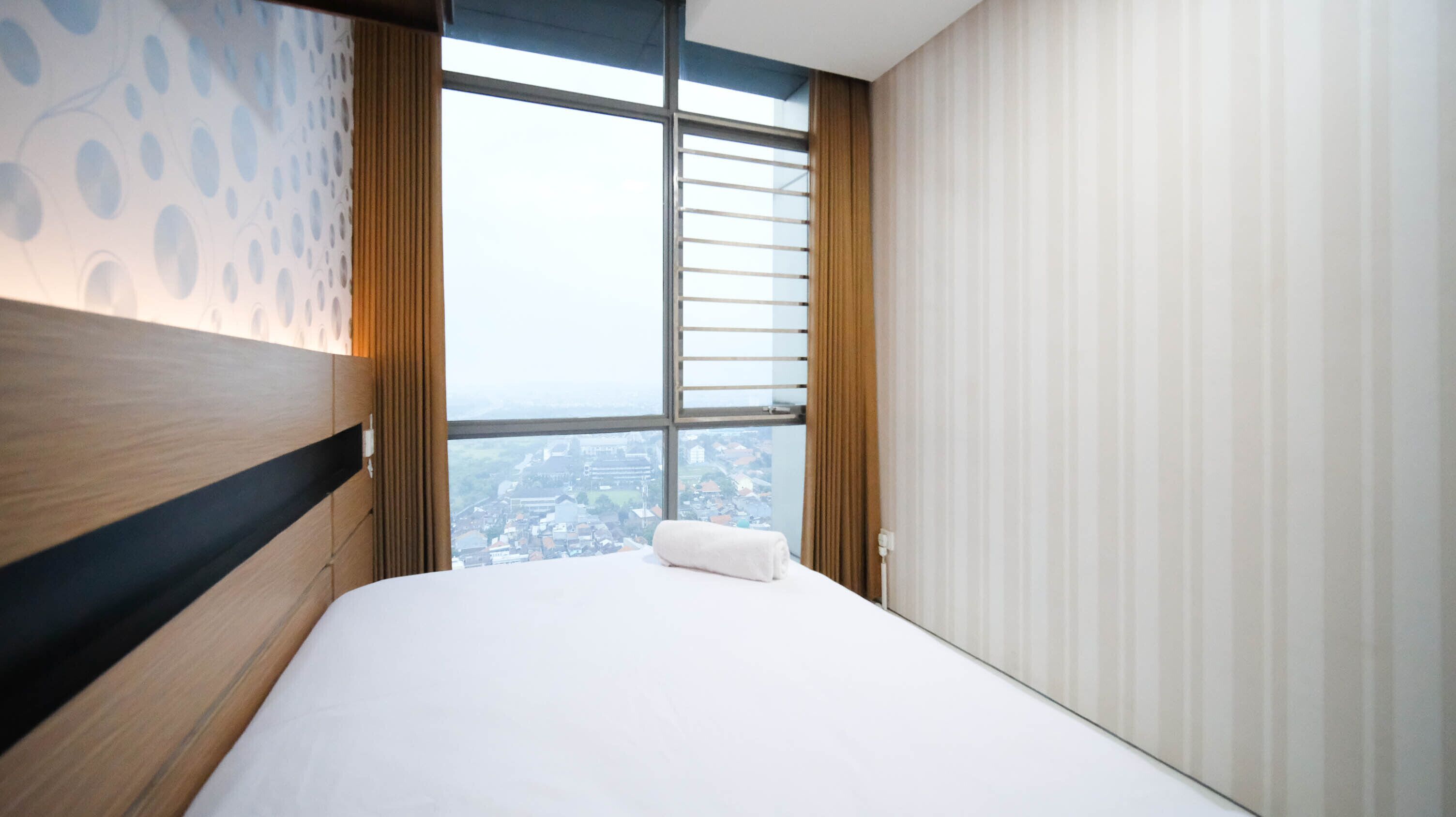 A modern hotel room with a large window, a neatly made bed, and a city view.
