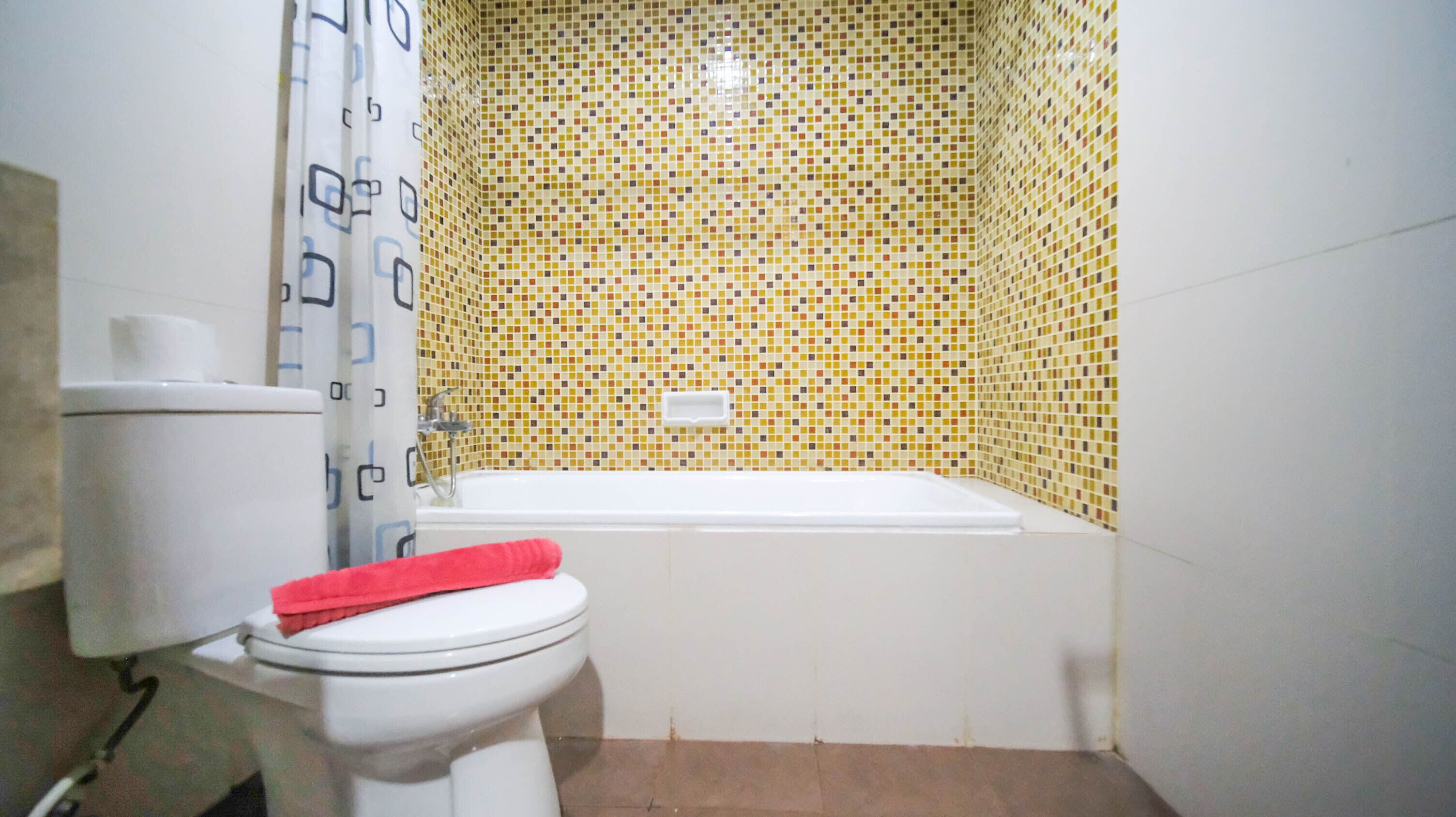 A bathroom with a toilet, a bathtub, and a shower curtain.