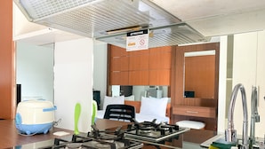 A kitchen with a gas stove, sink, and a sign indicating a smoking area. - Simply Look Studio Metropark Condominium Jababeka Apartment (Cikarang)
