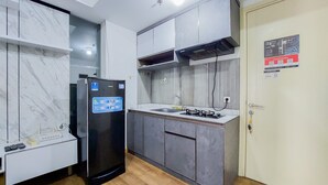 Een kleine keuken met een geïntegreerde koelkast, een gasfornuis en een spoelbak.