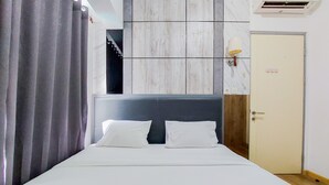Een hotelkamer met een bed, gordijnen, een wandairconditioner en een deur.