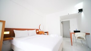 Una habitación de hotel con cama, escritorio, silla y puerta.