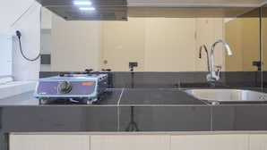 A kitchen with a black countertop, stainless steel sink, and a portable gas stove.
