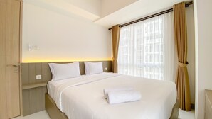 Ein Hotelzimmer mit einem großen Bett, zwei Kissen, einem Nachttisch und einem Fenster mit Vorhängen.