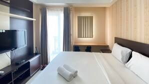 Una habitación de hotel con cama, televisor, escritorio y ventana con cortinas.