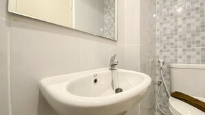 Kylpyhuone, jossa on valkoinen pesuallas, peili ja wc-istuin.