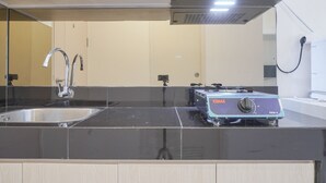 Cozinha com bancada preta, pia de aço inoxidável e fogão portátil.