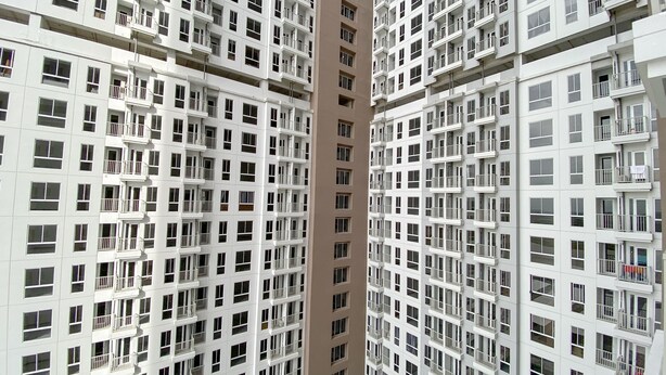 Um edifício residencial alto com várias varandas e fachada uniforme.
