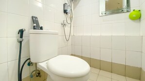 A bathroom with a toilet, a shower, and a mirror.