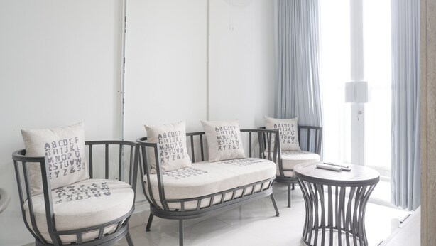 A modern room with two black metal chairs and a small round table, both with white cushions. - Exclusive Studio At Gold Coast Apartment (Jakarta)
