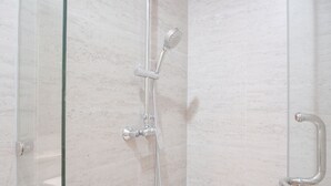A glass-enclosed shower with a handheld showerhead and a wall-mounted faucet. - Exclusive Studio At Gold Coast Apartment (Jakarta)