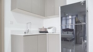 A compact kitchen with a modern design, including a built-in oven, a coffee maker, and a toaster. - Exclusive Studio At Gold Coast Apartment (Jakarta)