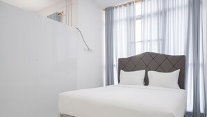 A modern hotel room with a large bed, a headboard, and a window with curtains. - Exclusive Studio At Gold Coast Apartment (Jakarta)