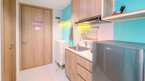 A compact kitchen with wooden cabinets, a stainless steel sink, and a built-in LG refrigerator. - Homey And Simply Look Studio Room At Bogor Icon Apartment (Bogor)