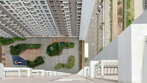 Un bâtiment moderne doté d’une façade originale, caractérisée par une grille de balcons et un jardin sur le toit.