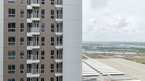 Un immeuble de grande hauteur doté de nombreux balcons et offrant une vue sur une vaste zone ouverte, avec des étendues d’eau et des infrastructures.