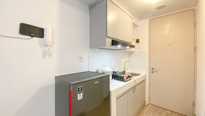 Une cuisine de taille réduite équipée d’un réfrigérateur, d’une cuisinière et d’un évier.