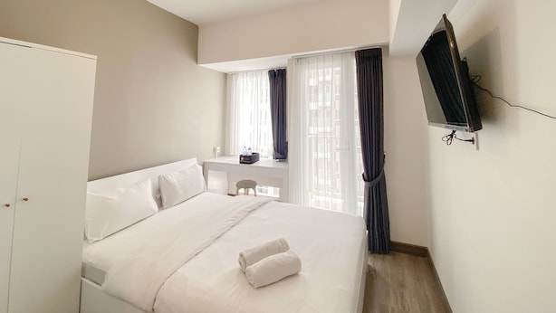 Une chambre d’hôtel avec un lit, un bureau, une télévision et une fenêtre avec des rideaux.