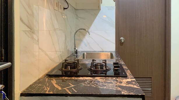 Una cucina compatta con piano cottura a gas, lavello e schienale in piastrelle di marmo bianco.