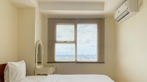Una camera d'hotel con un letto grande, un comodino con uno specchio e una finestra con persiane.