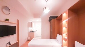 A hotel room with two beds, a TV, a small kitchenette, and a mirror. - Elegant And Cozy Studio Barsa City Apartment (Depok)