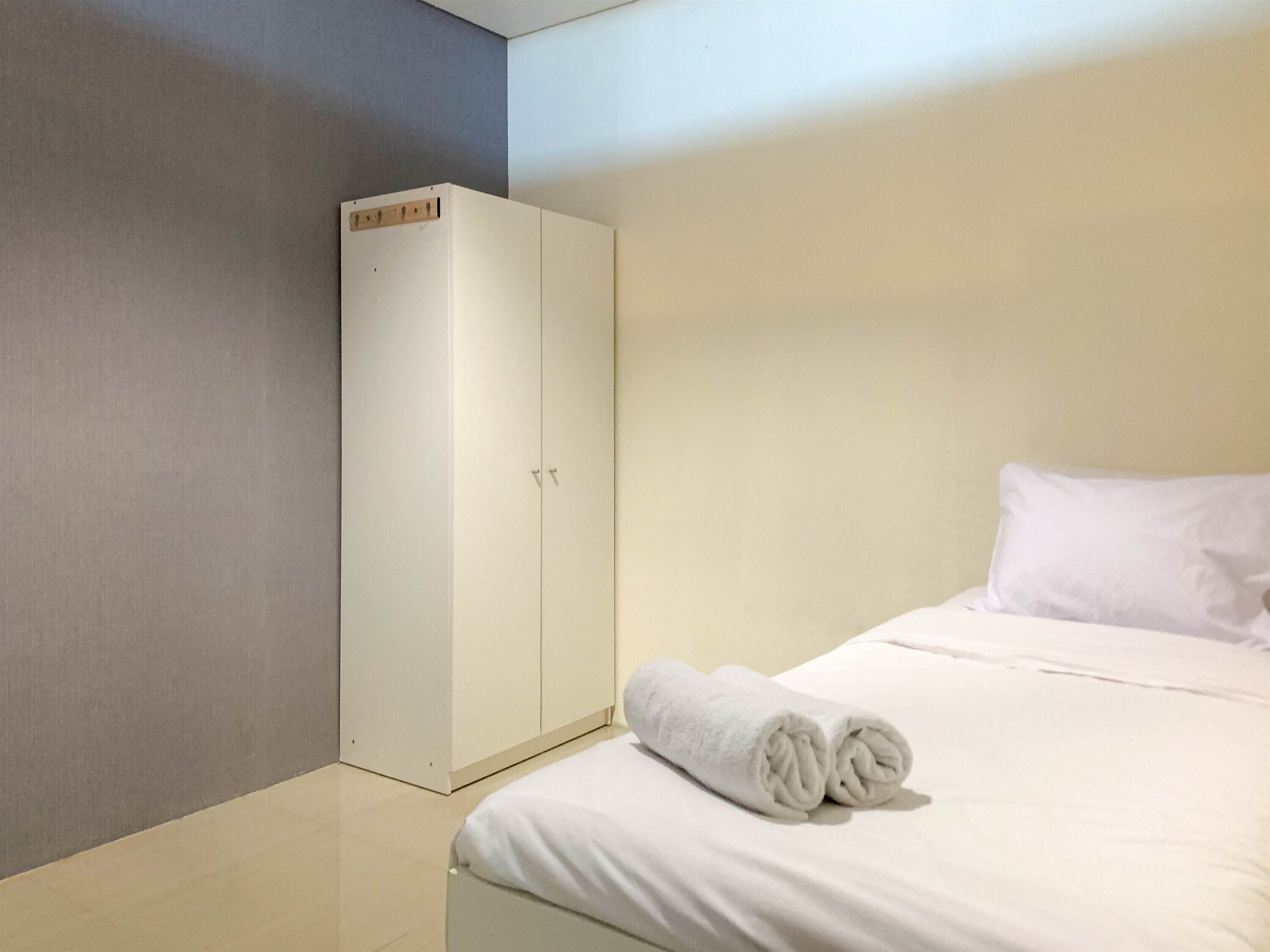 Ein Hotelzimmer mit einem Bett, einem weißen Kleiderschrank und einem Handtuch auf dem Bett.