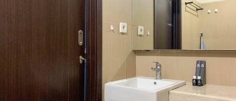 Un baño con un lavamanos blanco, un espejo y un perchero para toallas.