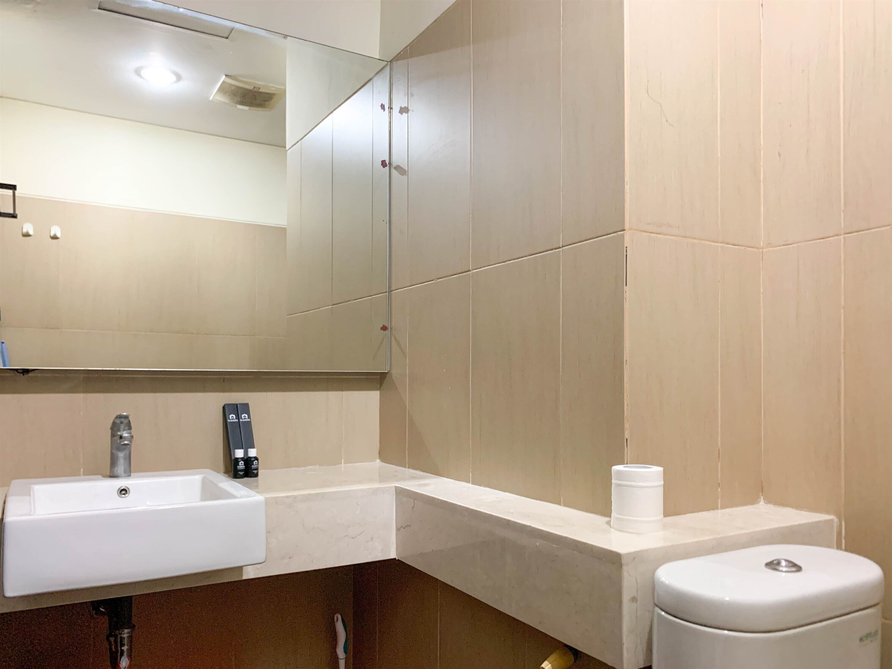 Un baño moderno con un lavamanos blanco, un inodoro y un espejo.
