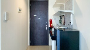 Een moderne badkamer met een donkere deur, een witte plank met toiletartikelen en een zichtbare lichtschakelaar.