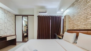 A hotel room with a bed, a wardrobe, a mirror, a brown curtain, and an air conditioning unit. - Nice Studio At 18Th Floor Atria Residences Gading Serpong Apartment (Gading Serpong)