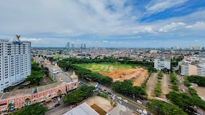A cityscape with a mix of modern and historic buildings, a large open field, and a clear sky. - Nice Studio At 18Th Floor Atria Residences Gading Serpong Apartment (Gading Serpong)