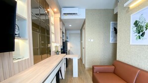 A modern living room with a wooden coffee table, a brown leather sofa, and a flat-screen TV mounted on the wall. - Great Choice And Comfort Stay 2Br At Patraland Urbano Apartment (Bekasi)