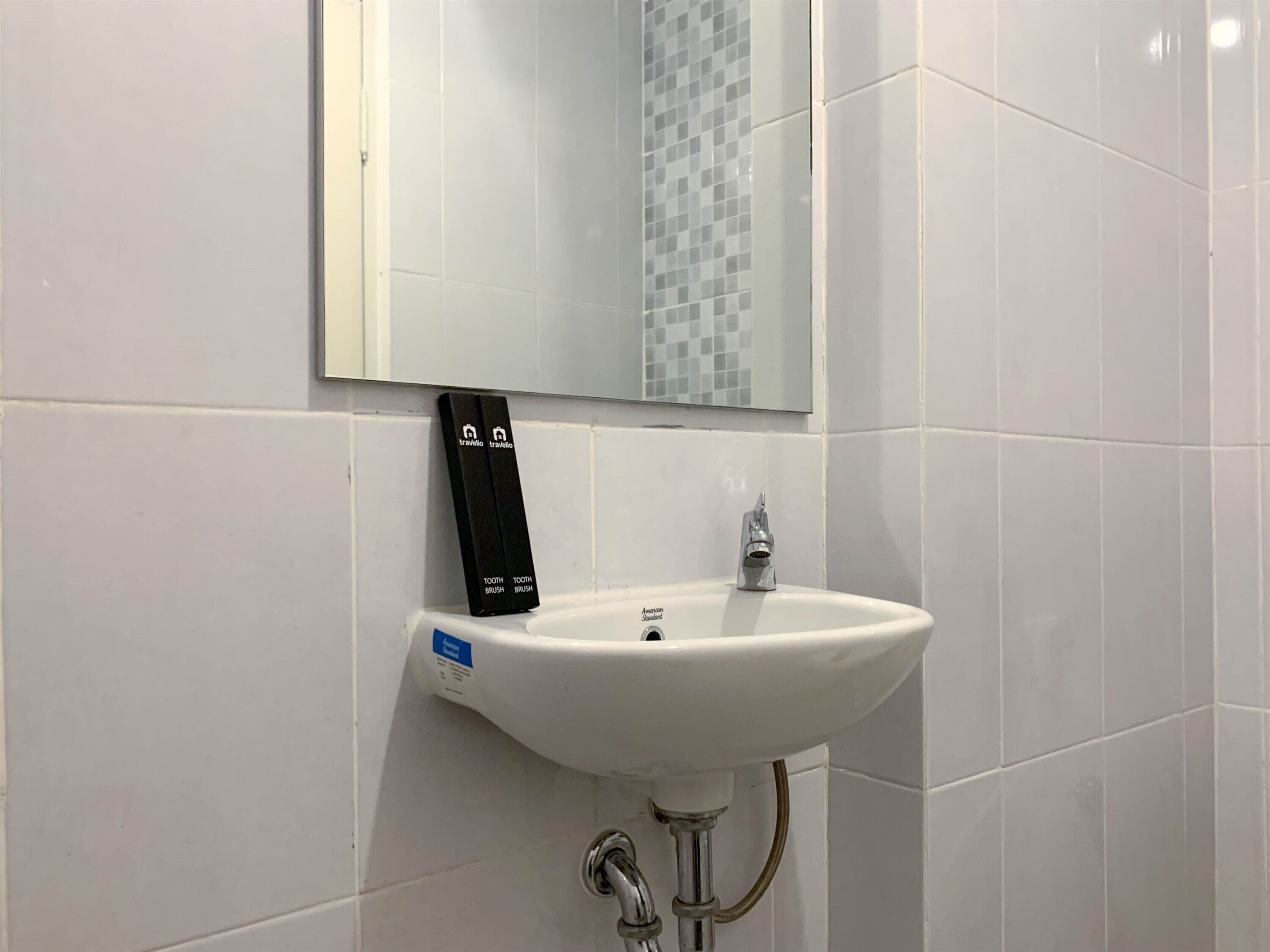 A white bathroom sink with a mirror above it, a toothbrush holder, and a faucet.