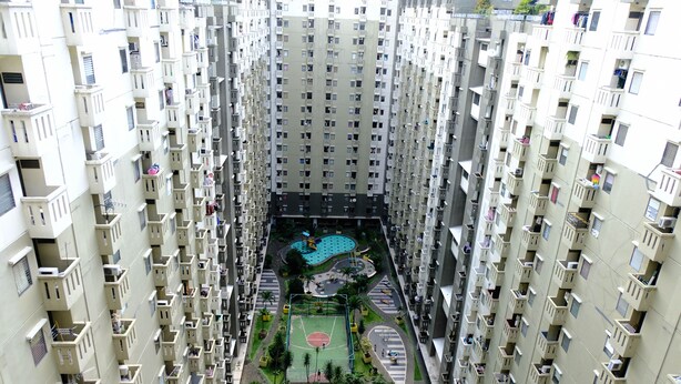 A high-rise residential building with multiple balconies, a central courtyard with a swimming pool, and a basketball court. - Good Choice 2Br At 12Th Floor Gateway Ahmad Yani Cicadas Apartment (Bandung)