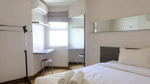 A hotel room with a bed, a desk, a chair, and a large mirror. - Homey 1Br At Apartment Parahyangan Residence (Bandung)