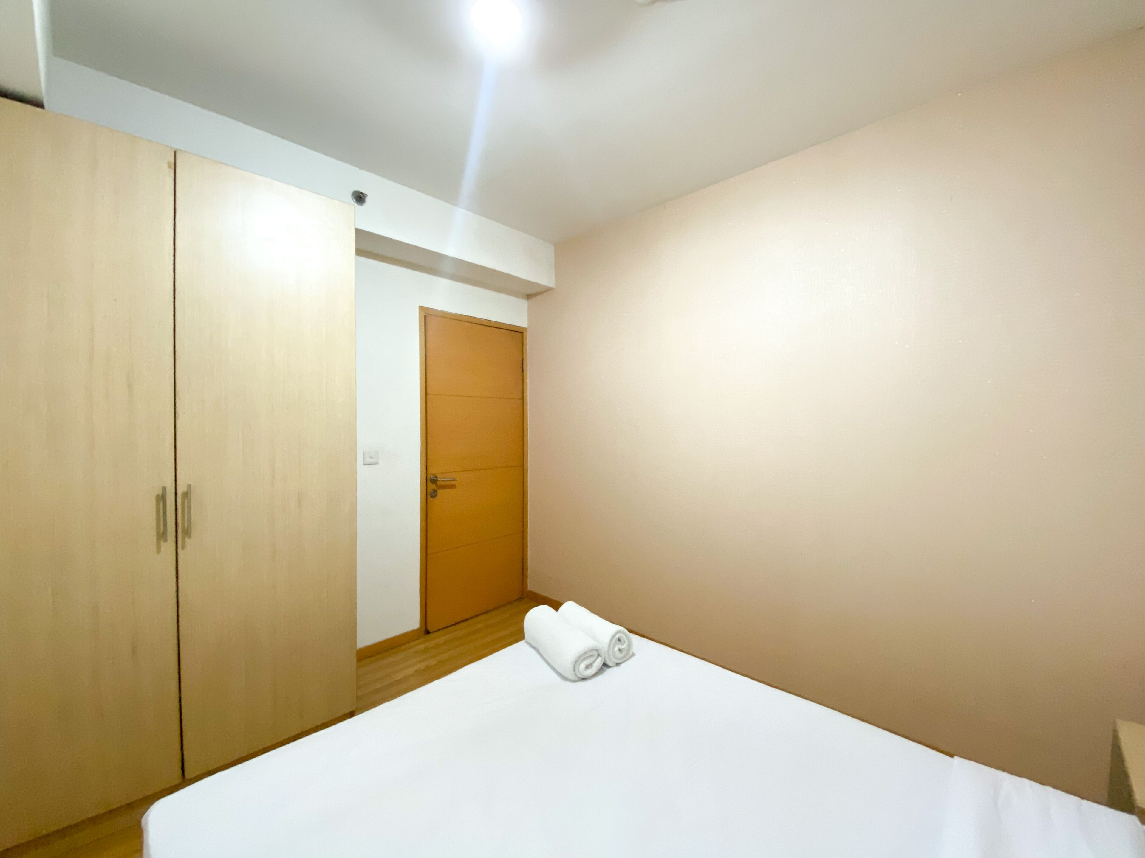A bedroom with a bed, a wooden wardrobe, and a door.