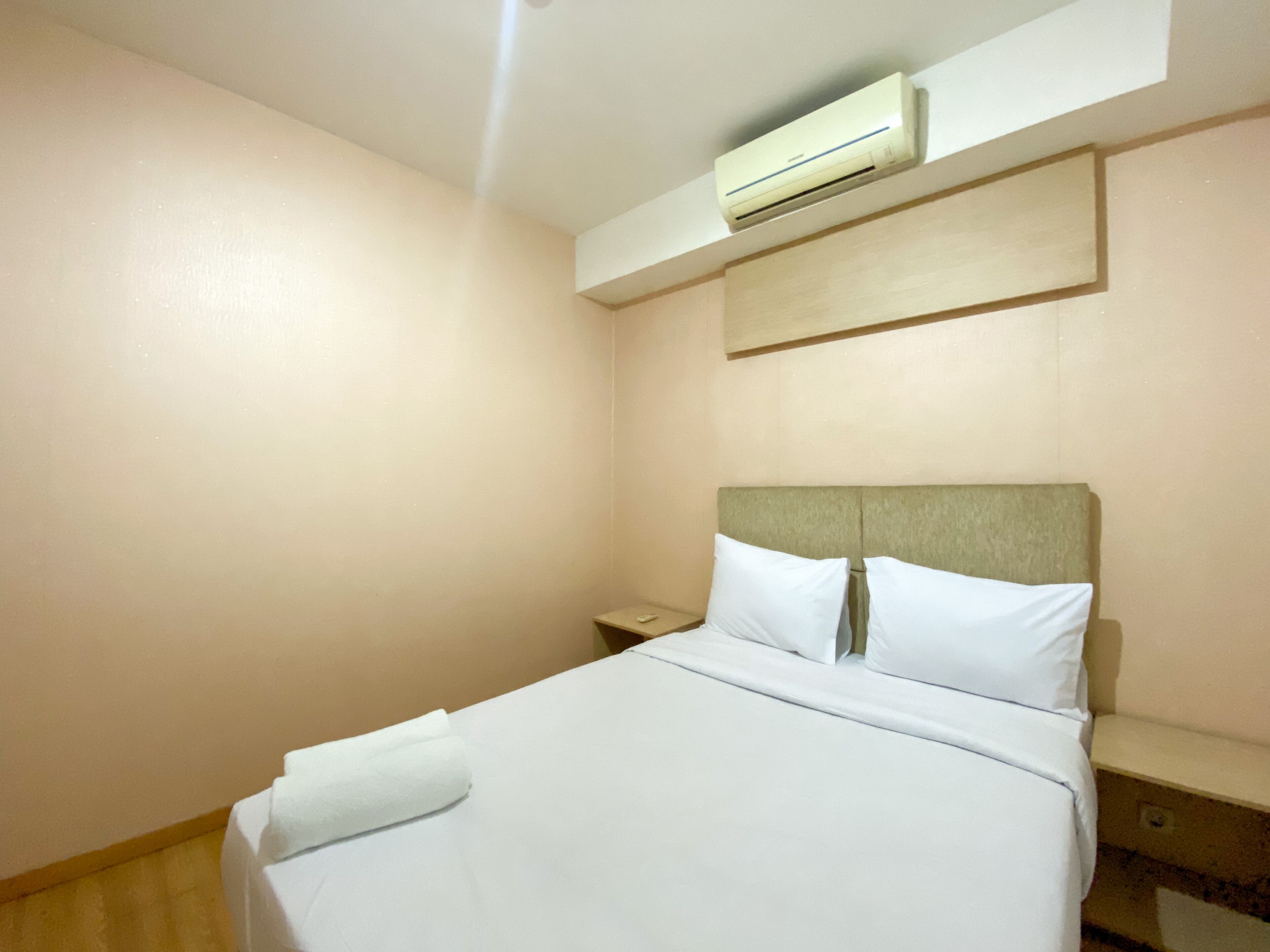 Una camera d'albergo con un letto, un comodino, un condizionatore d'aria e un pavimento in legno.