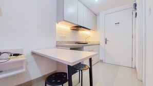 Una cocina pequeña con armarios blancos, una encimera y una sola silla.