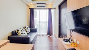 Una sala de estar moderna con un sofá, un televisor de pantalla plana y un escritorio con una computadora portátil y cables.