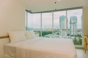 Une chambre avec une grande fenêtre, un lit et une vue sur le paysage urbain.