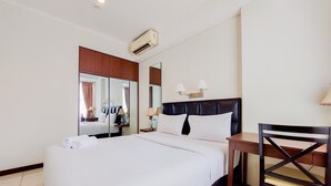 A hotel room with a large bed, a wooden nightstand, a desk, a chair, and a mirror. - Elegant And Tidy 1Br Apartment Silkwood Residences (Tangerang)