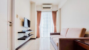 A modern living room with a flat-screen TV, a sofa, a coffee table, and a built-in shelf with electronic devices. - Elegant And Tidy 1Br Apartment Silkwood Residences (Tangerang)