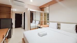 A hotel room with a bed, a desk, a wardrobe, and a mirror. - Homey Studio At Patraland Amarta Apartment (Ngaglik)