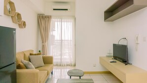 A modern living room with a sofa, a flat-screen TV, a coffee table, and a window with curtains. - Well Furnished 2Br Apartment M-Town Residence Near Mall (Gading Serpong)