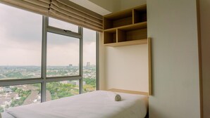 A bedroom with a large window, a bed, and built-in wooden shelves. - Well Furnished 2Br Apartment M-Town Residence Near Mall (Gading Serpong)